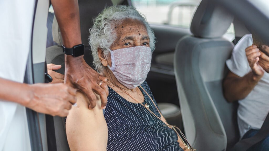 A segunda dose da vacina CoronaVac aplicada no braço de Evaristina de Rosa Lima, de 100 anos, no drive-thru da Arena Fonte Nova nesta quarta-feira (3),